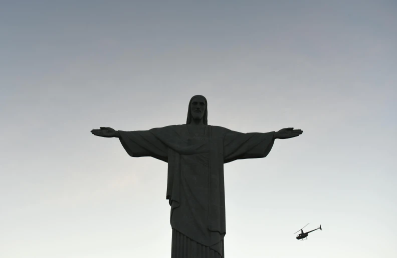 the statue of jesus is flying with a helicopter behind it