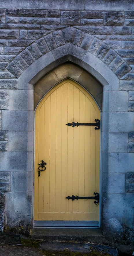 a yellow door with iron roddles above and below