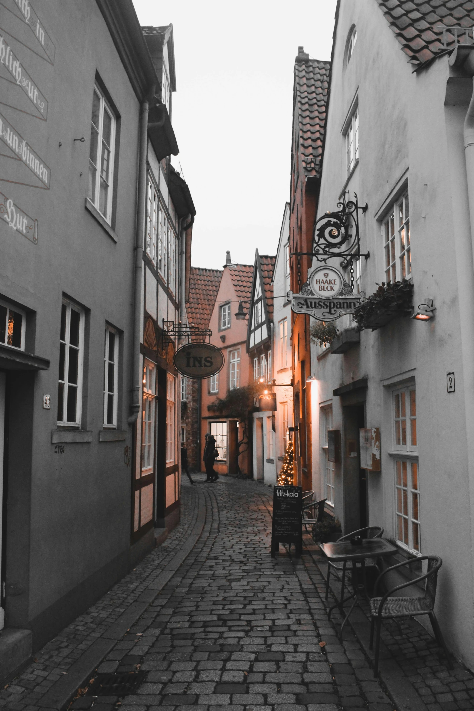 a cobblestone street is shown with christmas lights on the buildings