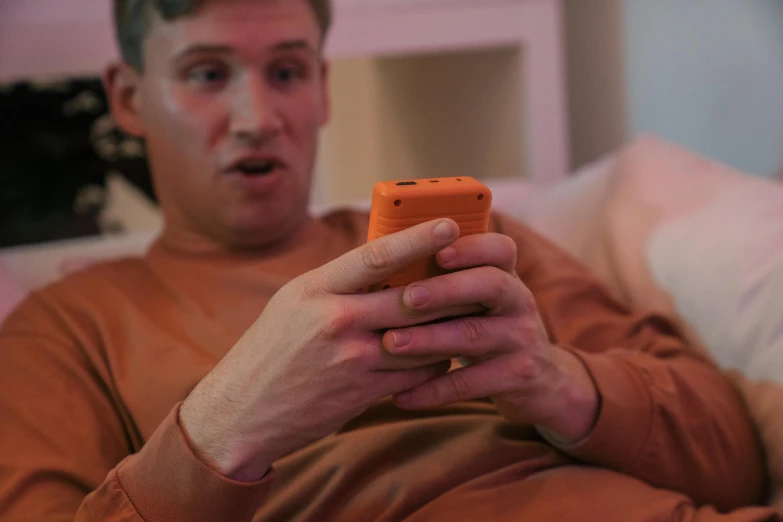 a man sits on a couch holding his cell phone