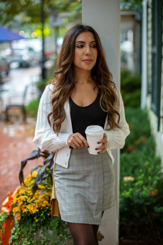 the woman is holding a cup outside by the building