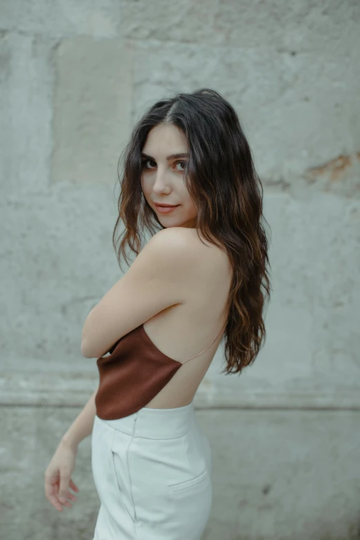 a woman in white pants and brown top posing for a po