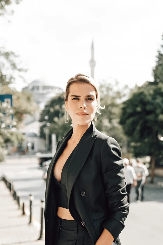 a young woman in a black suit standing next to a street