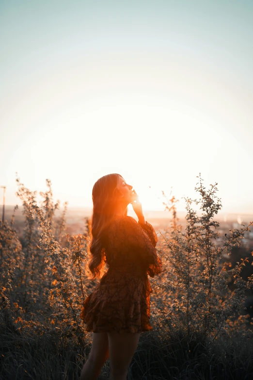 a woman standing on the grass in front of the sun