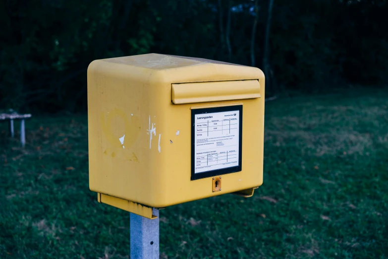 a yellow box on a metal pole in a grassy area