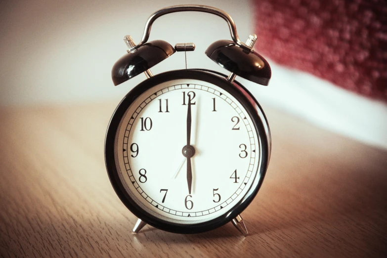 a metal alarm clock is displayed on a wooden table