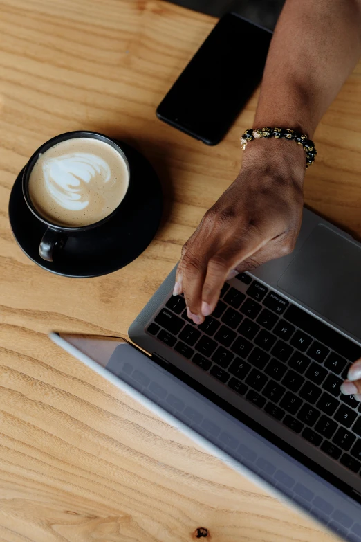 hands typing on a laptop keyboard while sitting at a table