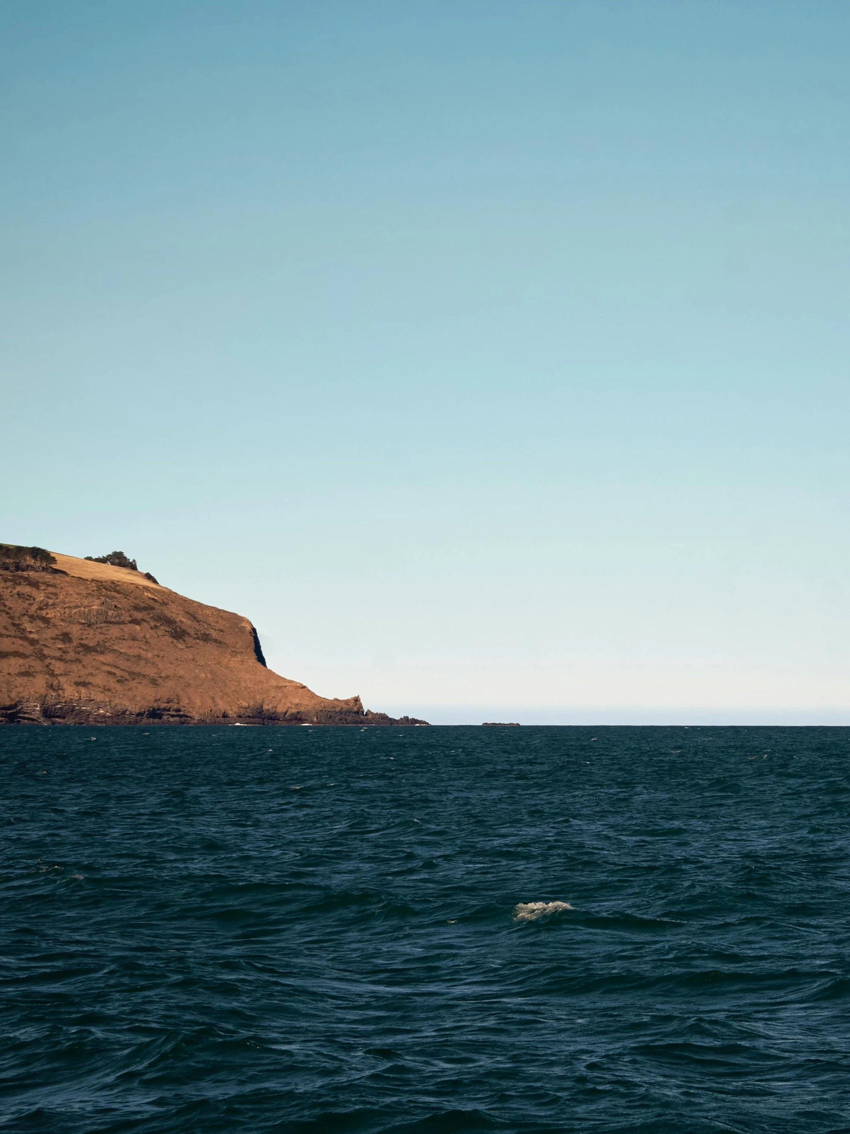 a person is riding on a wave near a mountain