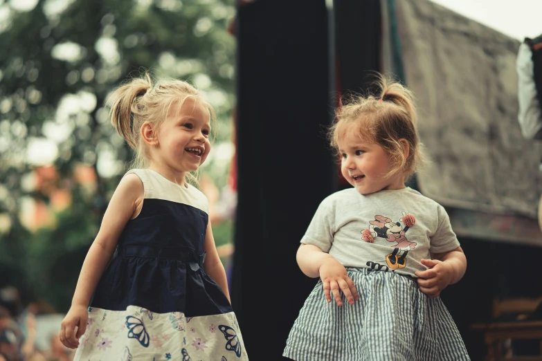 two little girls standing next to each other on top of a stage