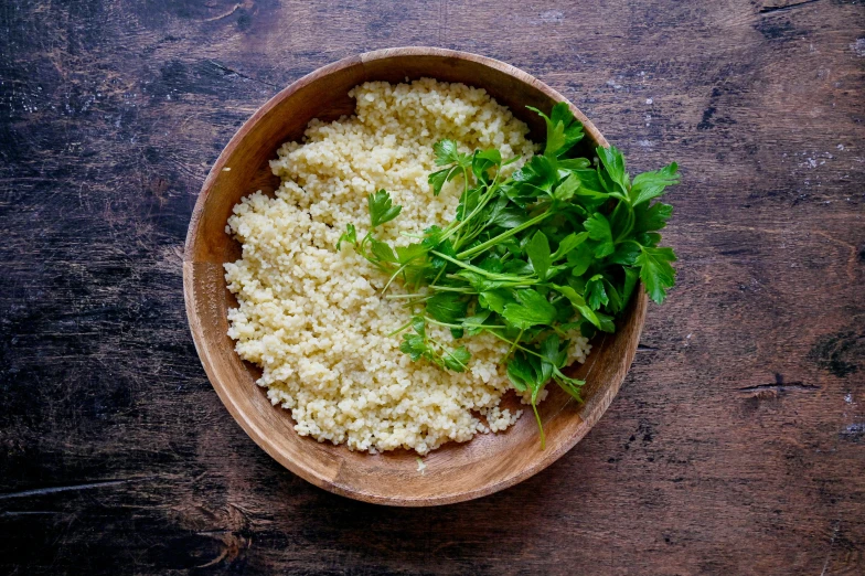 a wooden bowl full of rice and greens