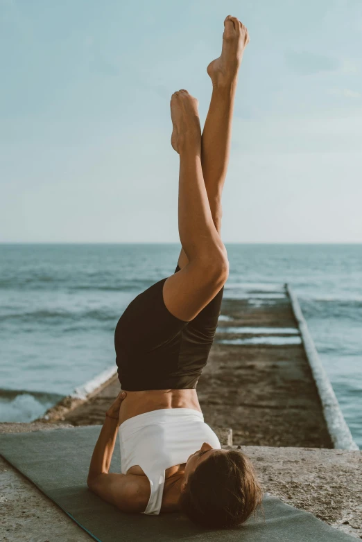 a woman doing yoga on her stomach near the water