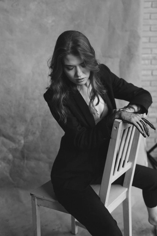 a woman sitting on a chair wearing a suit and heels