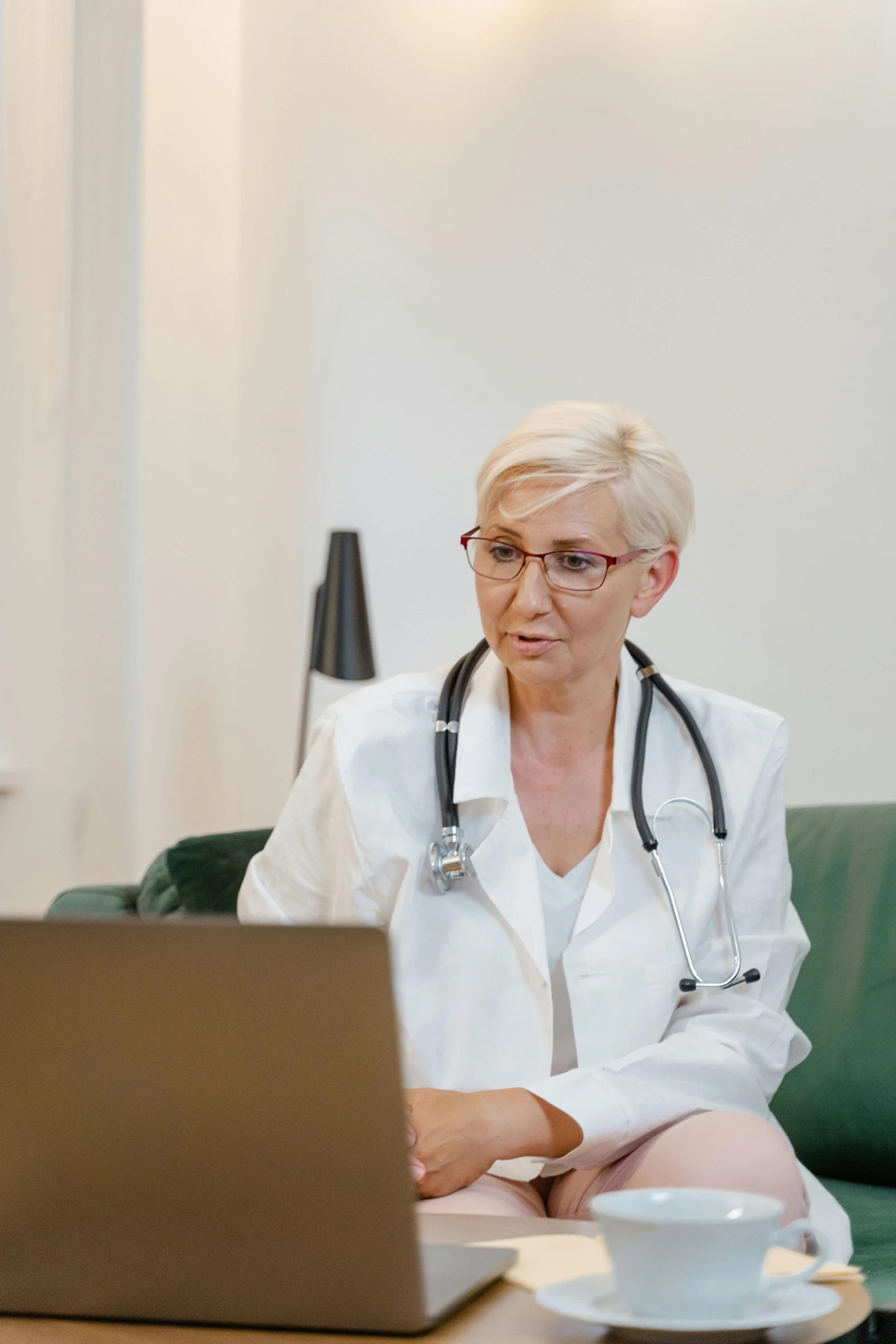 a female doctor sitting on her couch typing on her computer