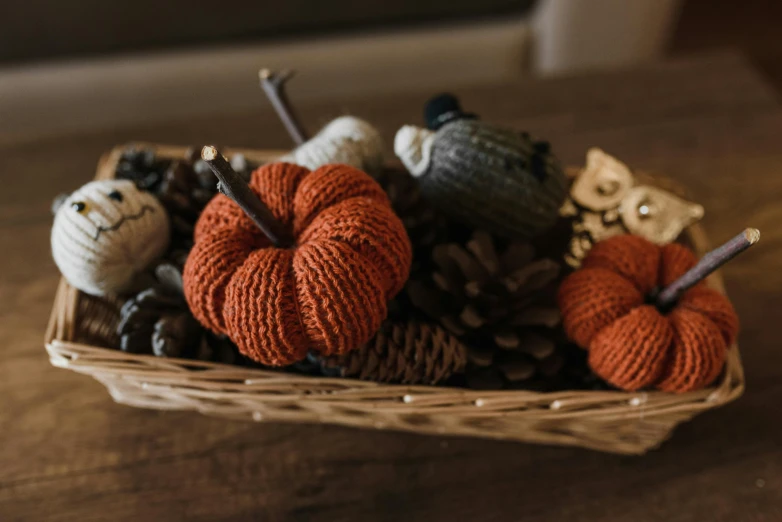 a basket filled with knit pumpkins on top of a table