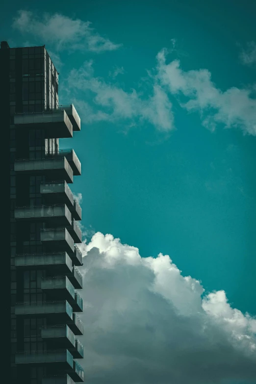 a tall, skinny building is surrounded by gray clouds