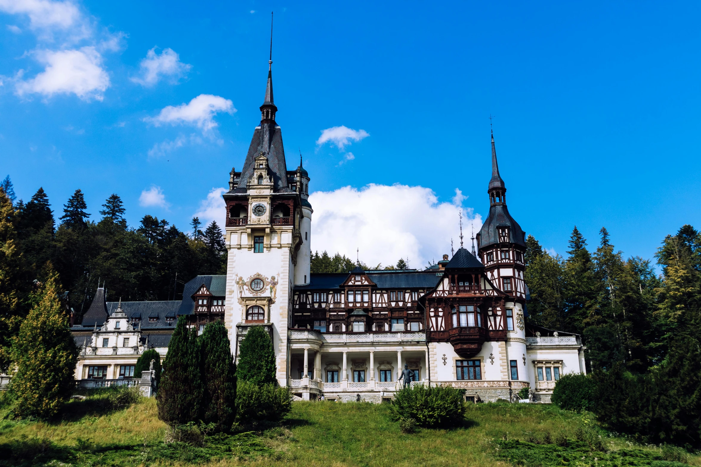 an old white building with towers with a clock on top