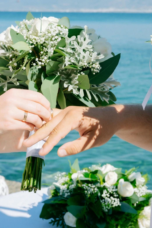 a person in a wedding dress places an engagement ring on the bride's finger