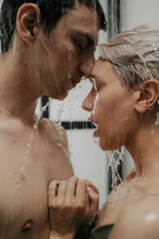 two people face each other with the shower head above their backs