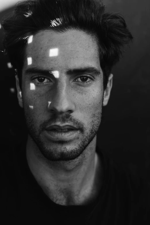 man in black shirt looking at camera with light reflection on face