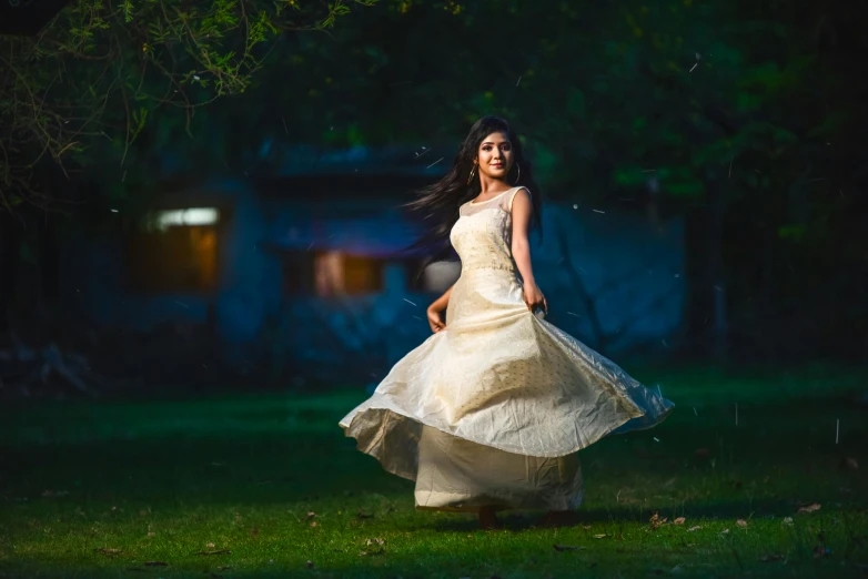 woman with dress flowing in the air in front of green tree