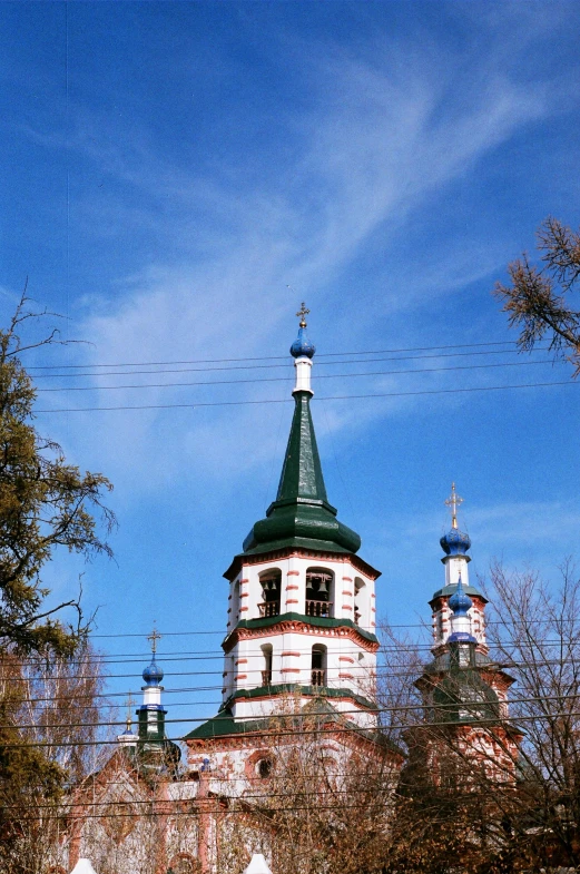 a church with a clock and tower, sitting next to some trees