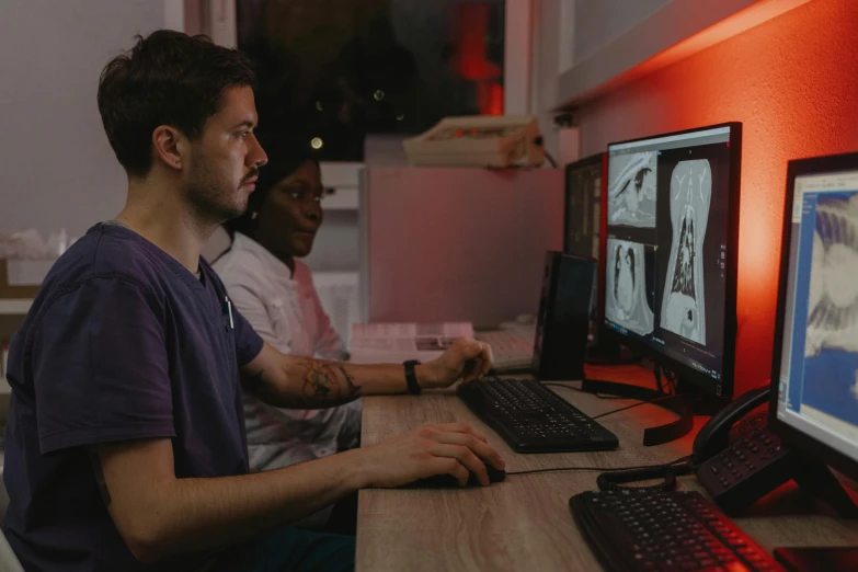 two men sitting in front of a computer monitor