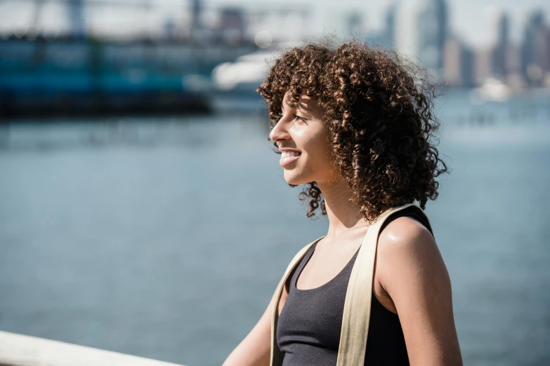 an african american woman smiles as she looks to the side with a city in the background