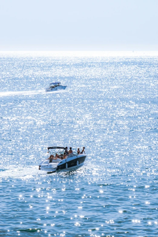 two motor boats on open water with a small boat in the distance