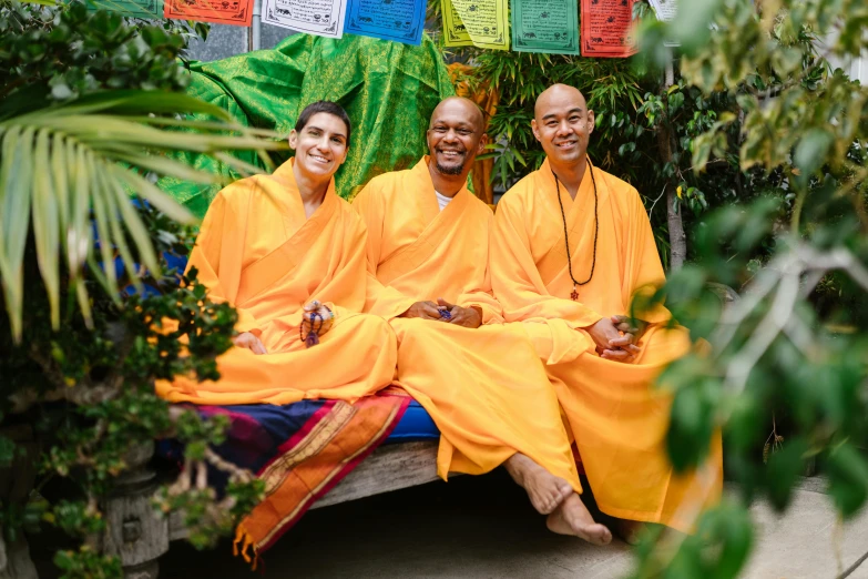 two men and one woman are sitting down on the bench