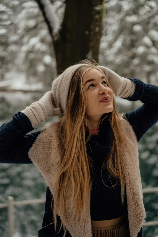 a young woman posing near a tree, in the snow