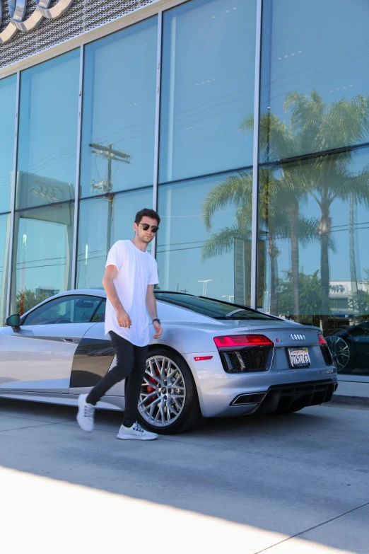 a young man in front of a silver car