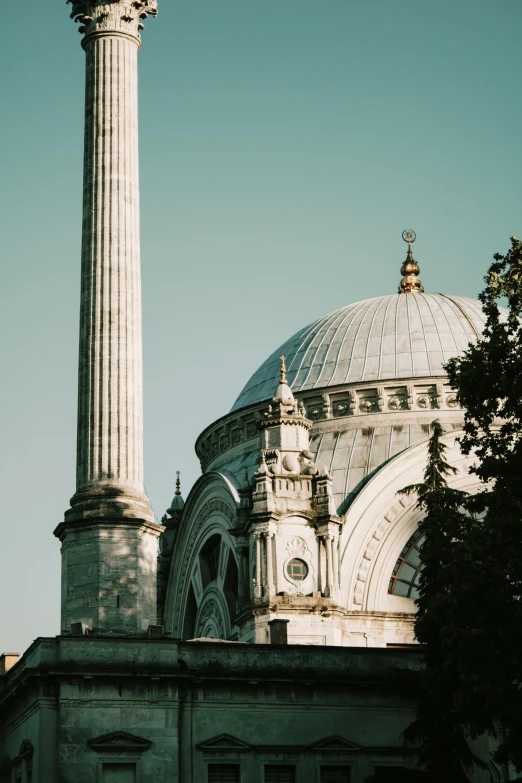 an old white dome building with a minature near trees