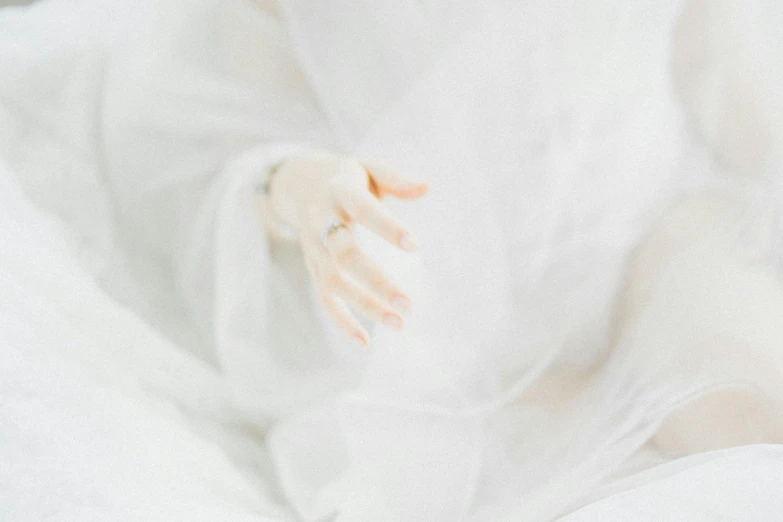 a baby's hands wearing white gloves laying on a blanket