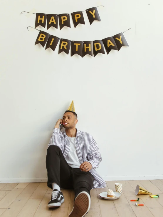 a man sits on the floor with a happy birthday banner