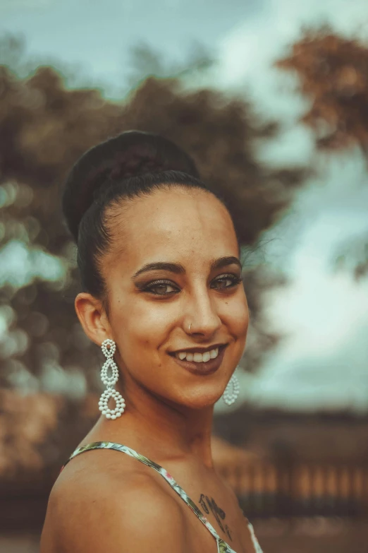 a woman with brown hair and diamond earrings smiles for the camera