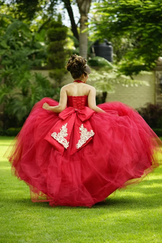 a little girl wearing a red dress in the grass