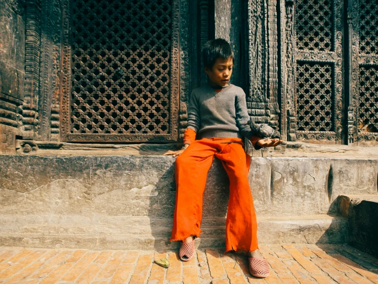 a small child sits on a ledge outside of a building