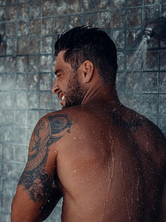 a shirtless man looking in the shower