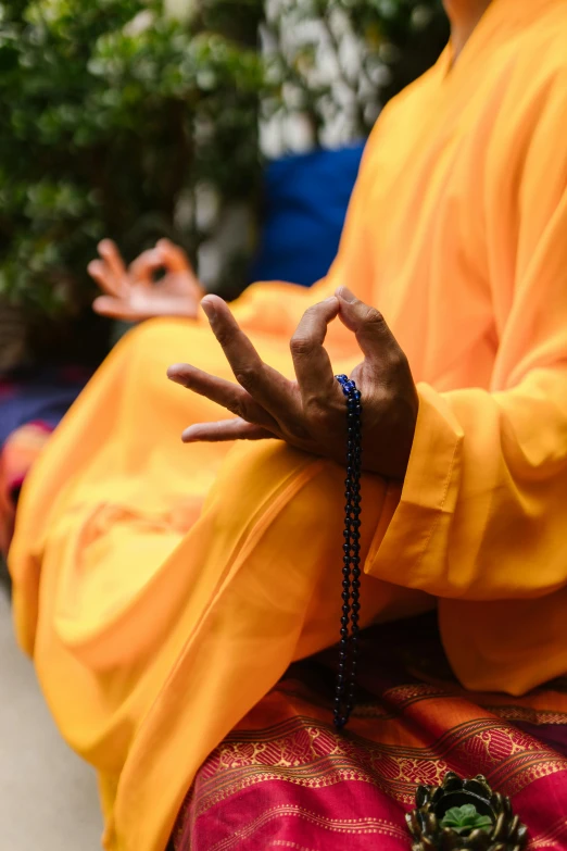 an image of a monk in a yellow outfit doing the namha sign