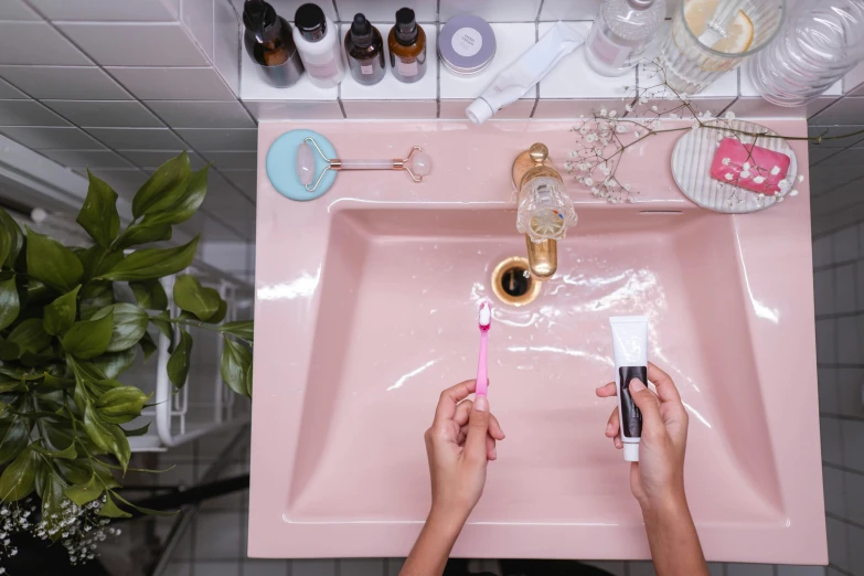 person with two hands on pink sink in room