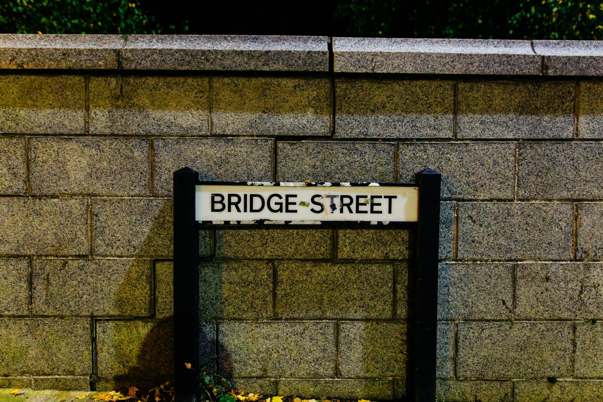 street sign on a concrete wall with a brick barrier behind it