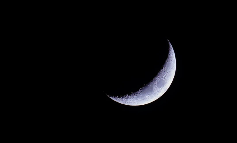 a crescent moon and some black skies with no clouds