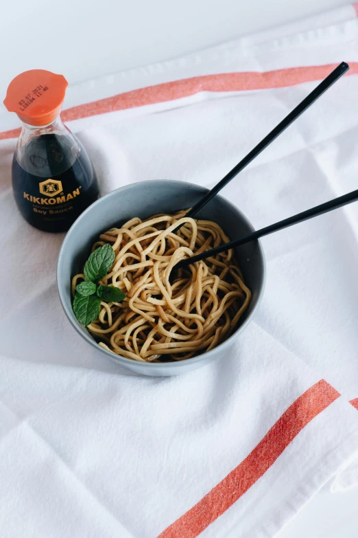 a bowl of pasta and a bottle of vinegar sit on the table