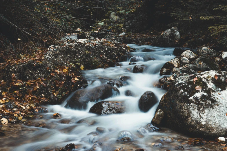 a stream of water running over rocks in the woods