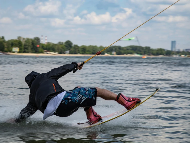 man wakeboarding on lake using string attached to his parachute