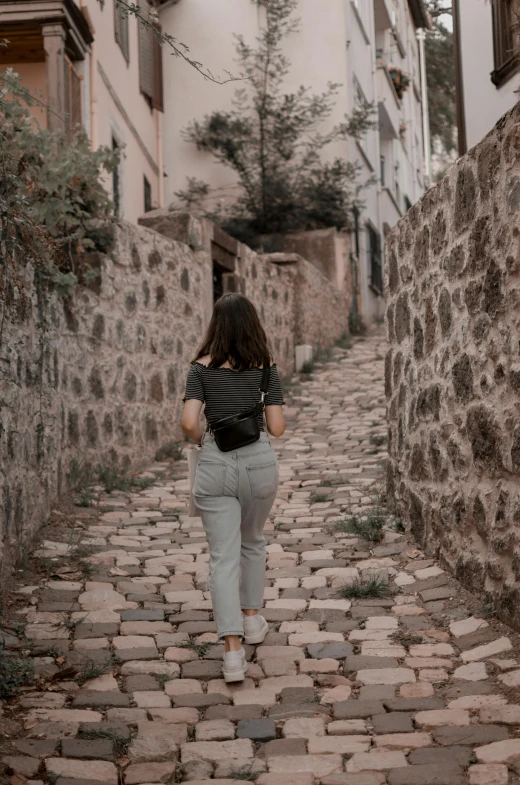 a woman walking down the cobble stone street