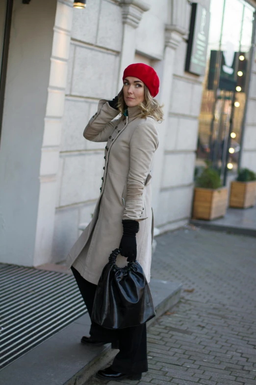 a woman wearing a long coat is walking down the street