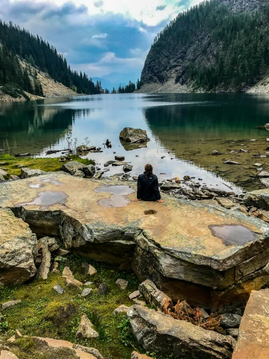 a woman sitting on top of a large rocky field