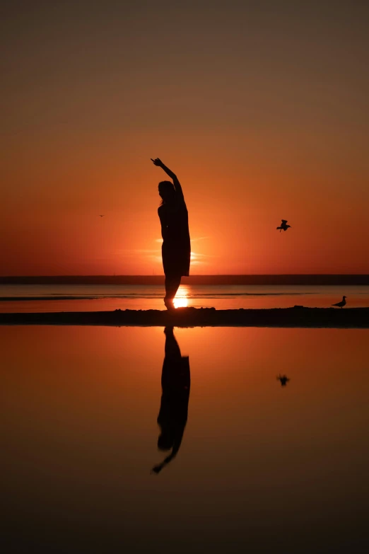 a person reaching for soing with the sun setting in the background