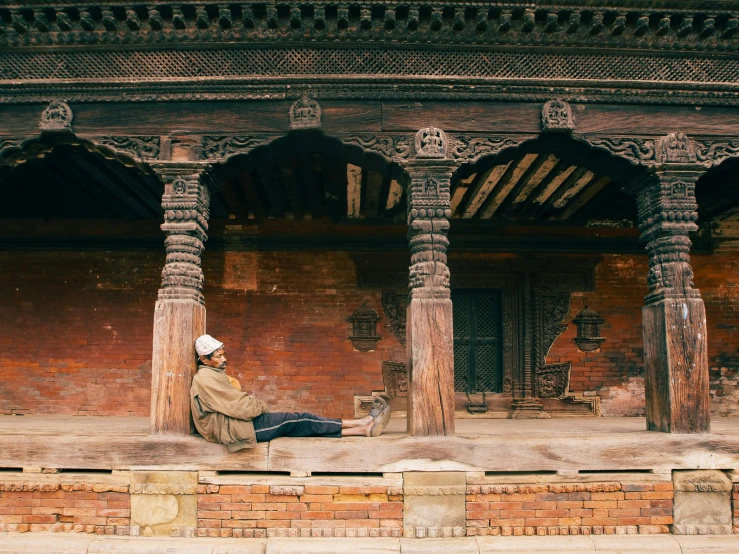 a man in a traditional indian dress sits on a ledge next to a wall